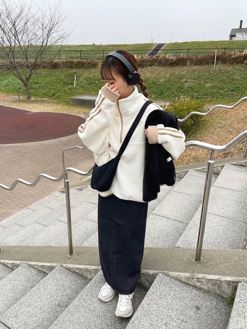 ブラック系のデニムスカート、ブラック系のショルダーバッグ、ホワイト系のスニーカーを着用したレディースの冬コーディネートの4枚目の写真