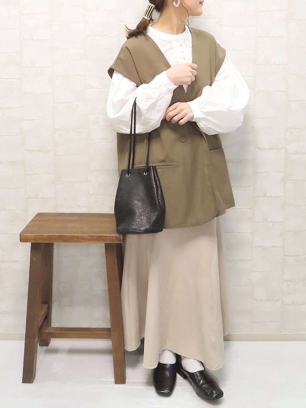 ホワイト系のシャツ/ブラウス、ブラウン系のベスト、ベージュ系のスカートを着用したレディースの冬コーディネートの2枚目の写真