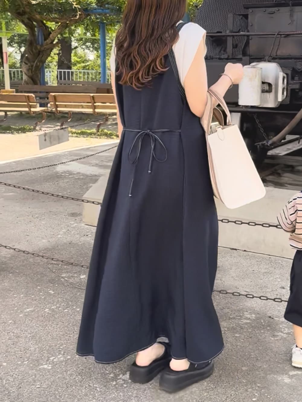 ブルー系のワンピース、ベージュ系のバッグ、ブラック系のサンダルを着用したレディースの夏コーディネートの4枚目の写真
