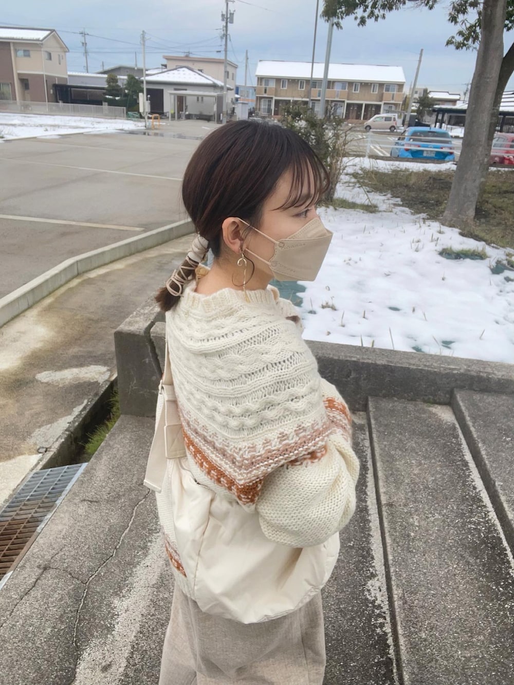 ブラウン系のニット/セーター、ホワイト系のショルダーバッグ、ベージュ系のスカートを着用したレディースの冬コーディネートの2枚目の写真