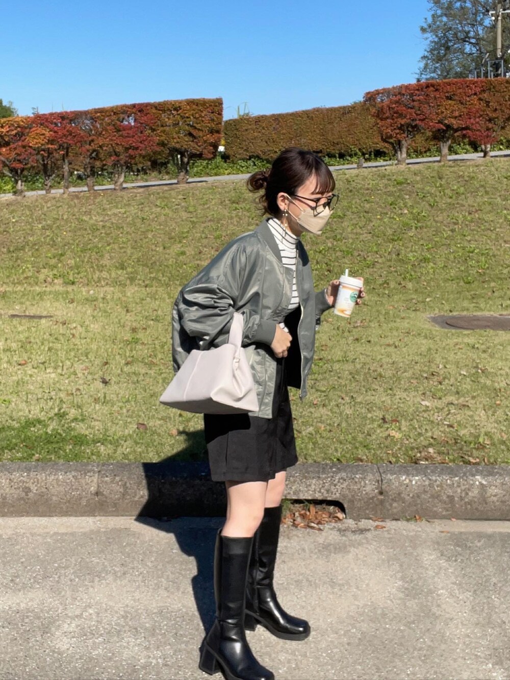 グリーン系のブルゾン、ホワイト系のニット/セーター、ブラック系のスラックスを着用したレディースの秋コーディネートの4枚目の写真