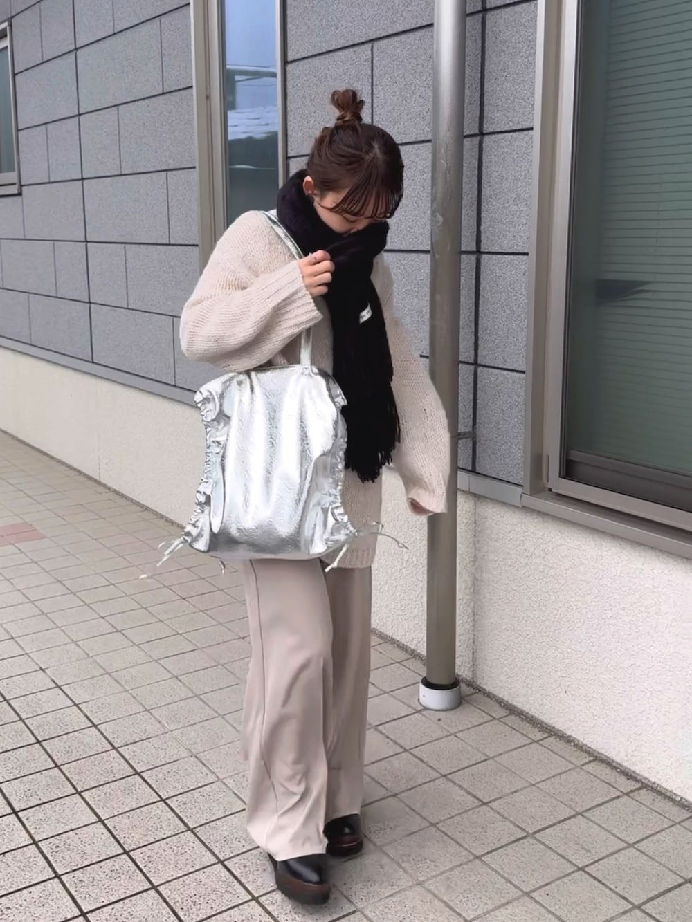 シルバー系のトートバッグ、ホワイト系のニット/セーター、ホワイト系のパンツを着用したレディースの冬コーディネートの2枚目の写真