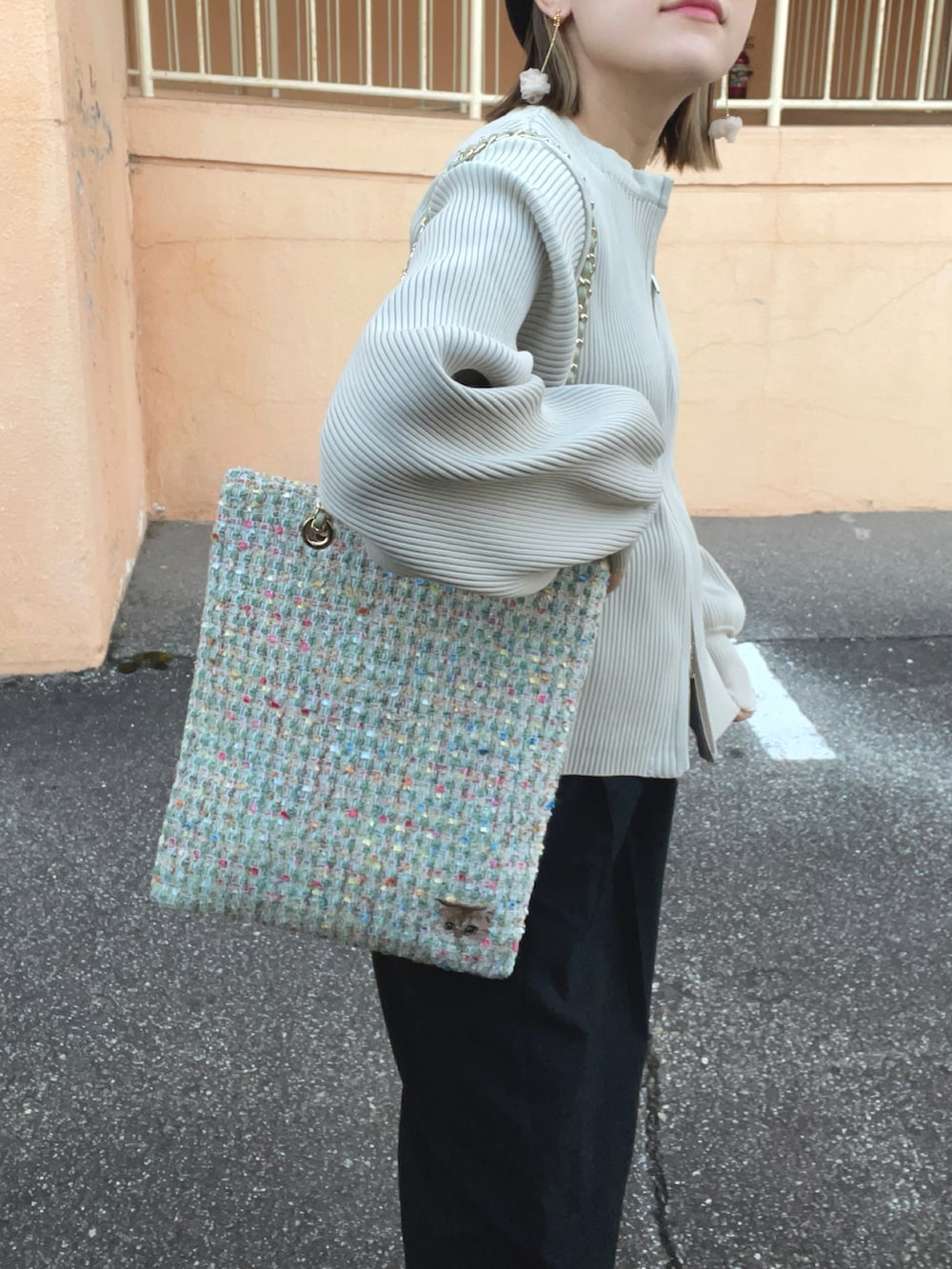 ホワイト系のカーディガン/ボレロ、グリーン系のトートバッグ、ブラック系のパンツを着用したレディースの秋コーディネートの3枚目の写真