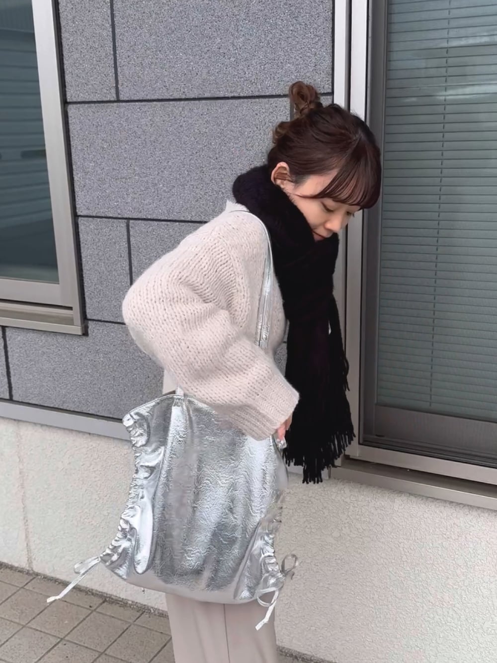 シルバー系のトートバッグ、ホワイト系のニット/セーター、ホワイト系のパンツを着用したレディースの冬コーディネートの4枚目の写真