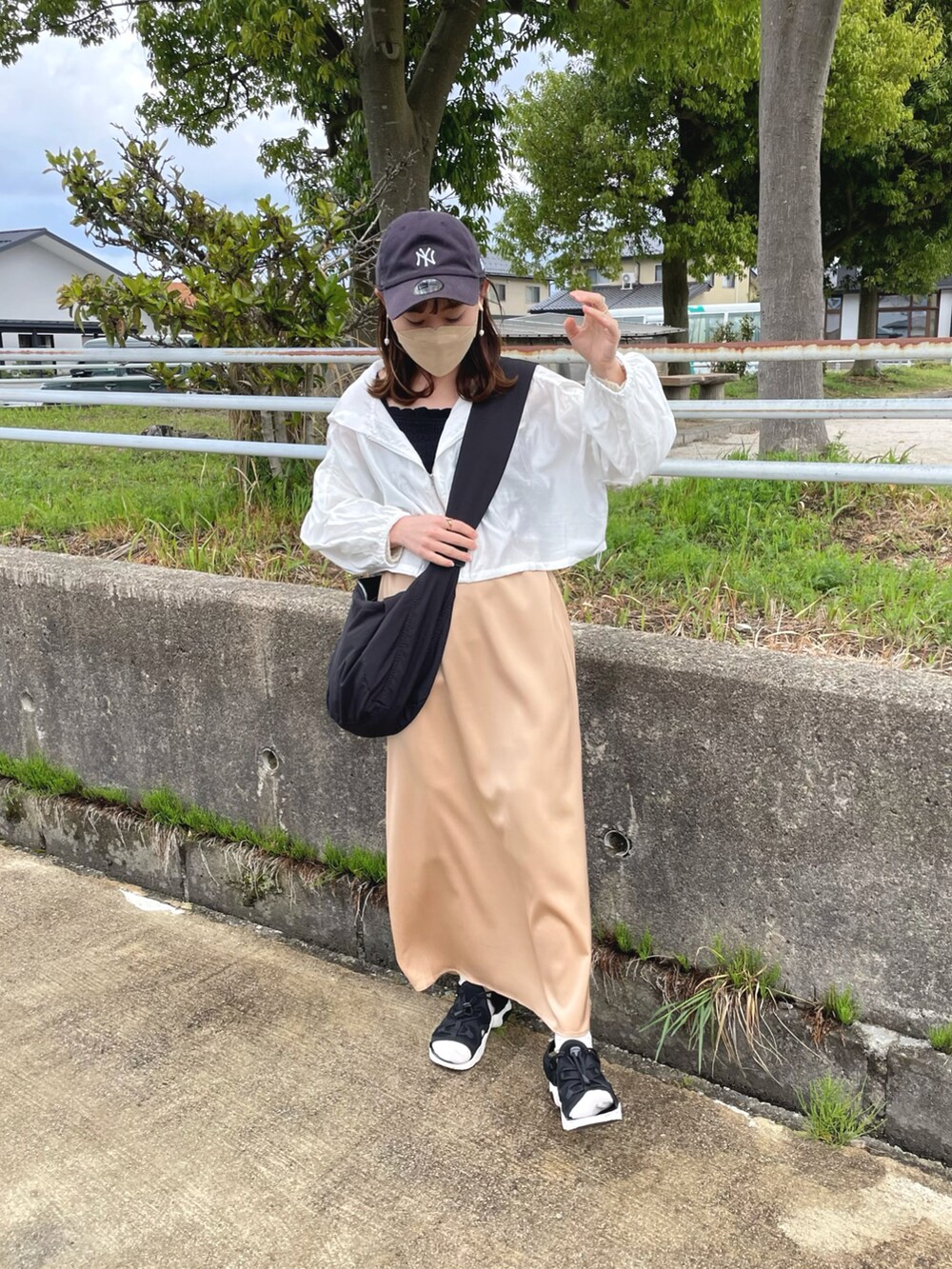 ベージュ系のスカート、ホワイト系のパーカー、ブラック系のキャミソールを着用したレディースの春コーディネートの2枚目の写真