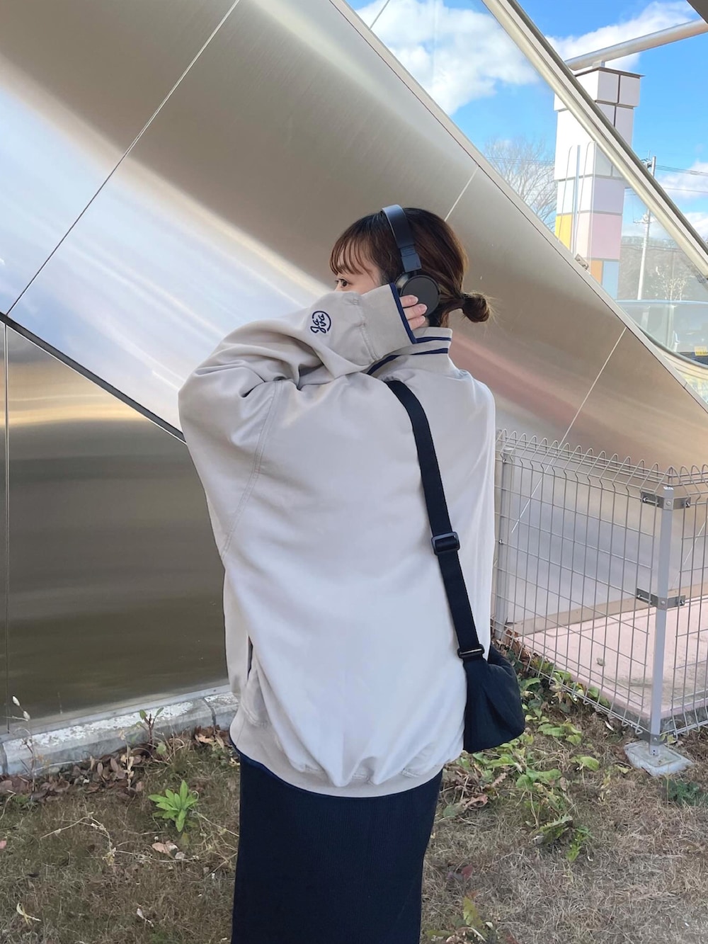 ベージュ系のスウェット、ブラック系のショルダーバッグ、ホワイト系のスニーカーを着用したレディースの冬コーディネートの2枚目の写真