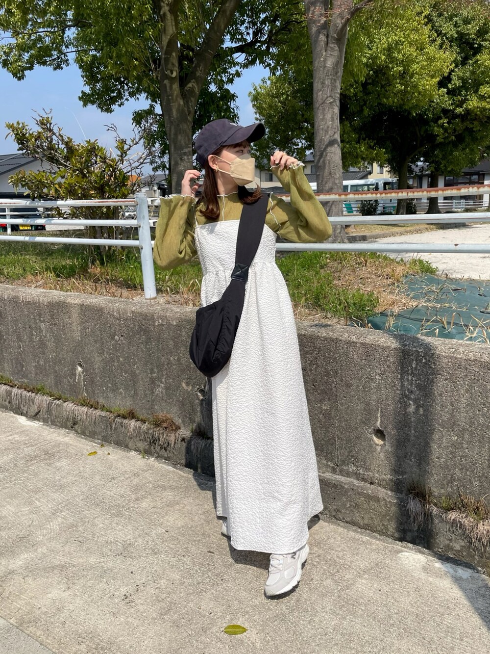 ホワイト系のワンピース、グリーン系のTシャツ/カットソー、ブラック系のショルダーバッグを着用したレディースの春コーディネートの2枚目の写真