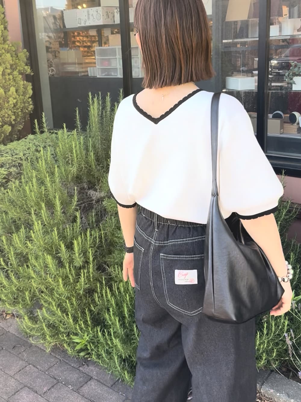 ホワイト系のTシャツ/カットソー、ブラック系のデニムパンツ、ブラック系のバッグを着用したレディースの夏コーディネートの2枚目の写真
