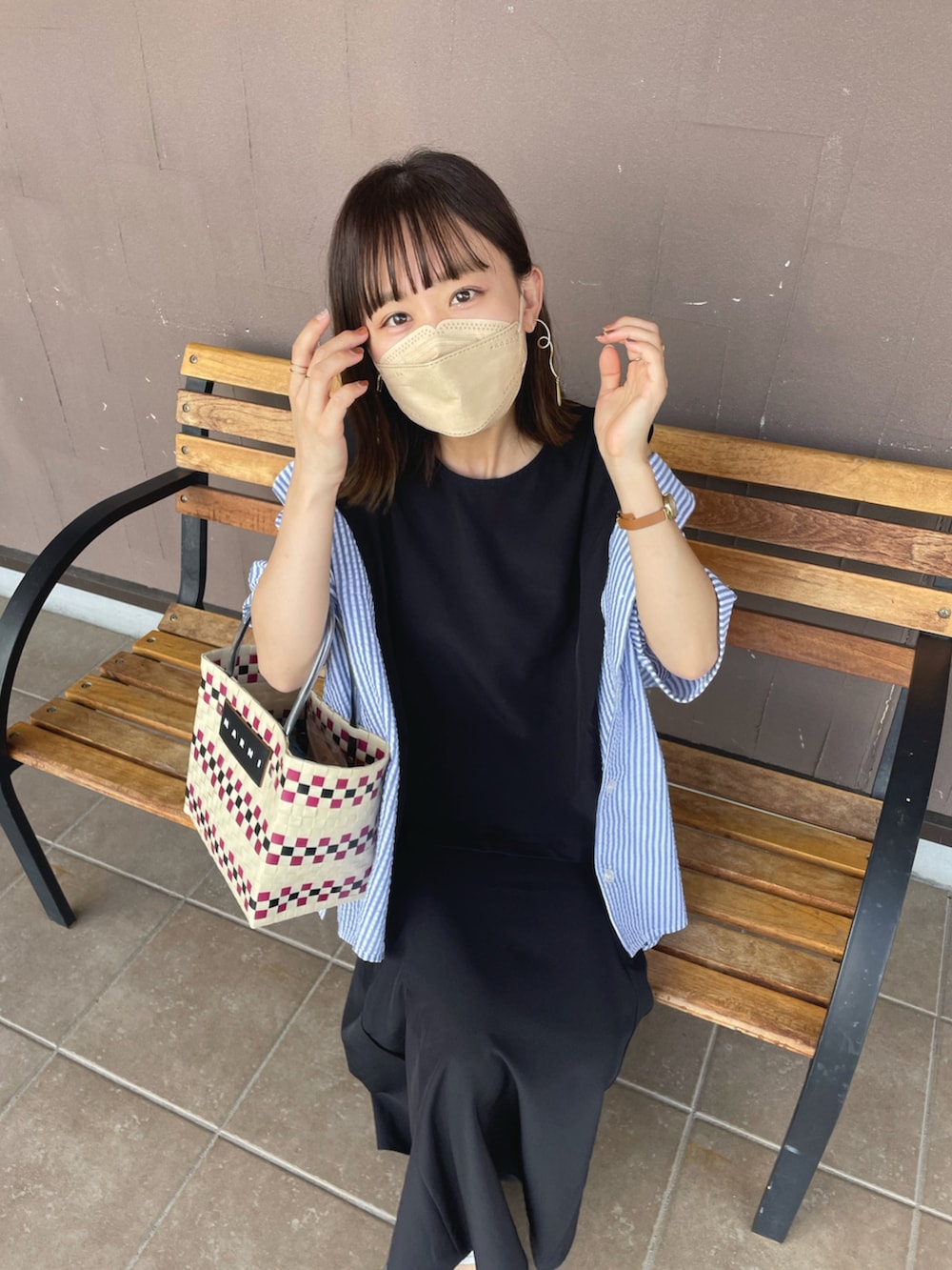 ブラック系のセットアップ、ベージュ系のサンダル、ホワイト系のかごバッグを着用したレディースの夏コーディネートの4枚目の写真