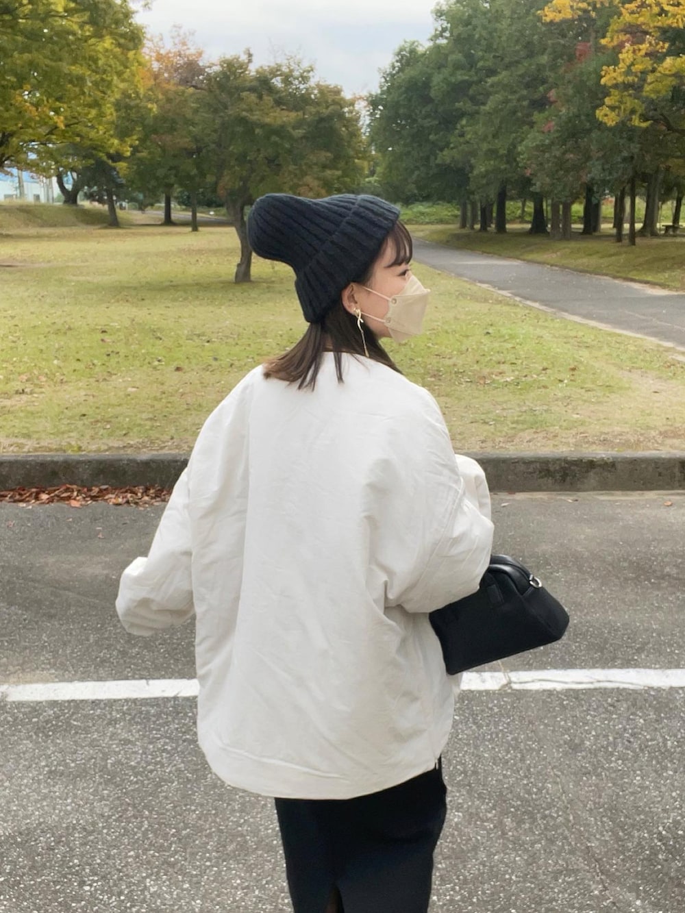 ホワイト系のダウンジャケット/コート、イエロー系のトップス、ブラック系のスカートを着用したレディースの秋コーディネートの3枚目の写真