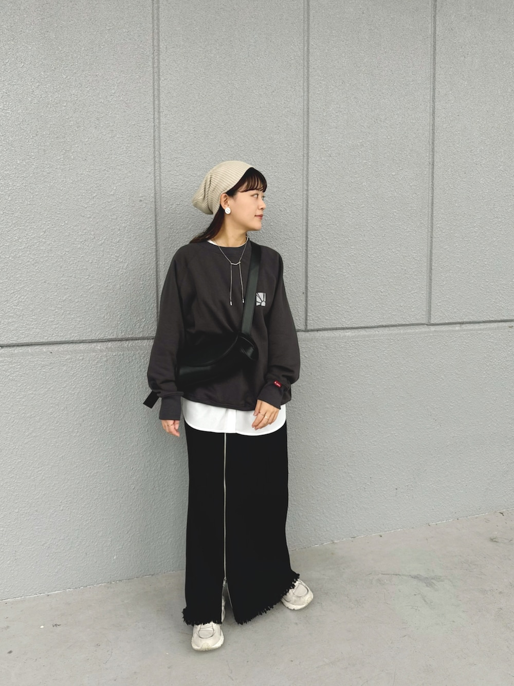 グレー系のスウェット、ブラック系のスカート、ブラック系のショルダーバッグを着用したレディースの秋コーディネートの3枚目の写真