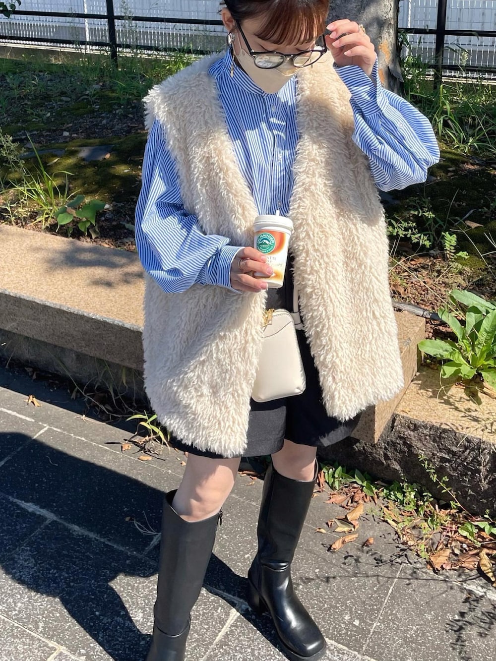 ブルー系のシャツ/ブラウス、ホワイト系のベスト、ブラック系のスラックスを着用したレディースの秋コーディネートの3枚目の写真