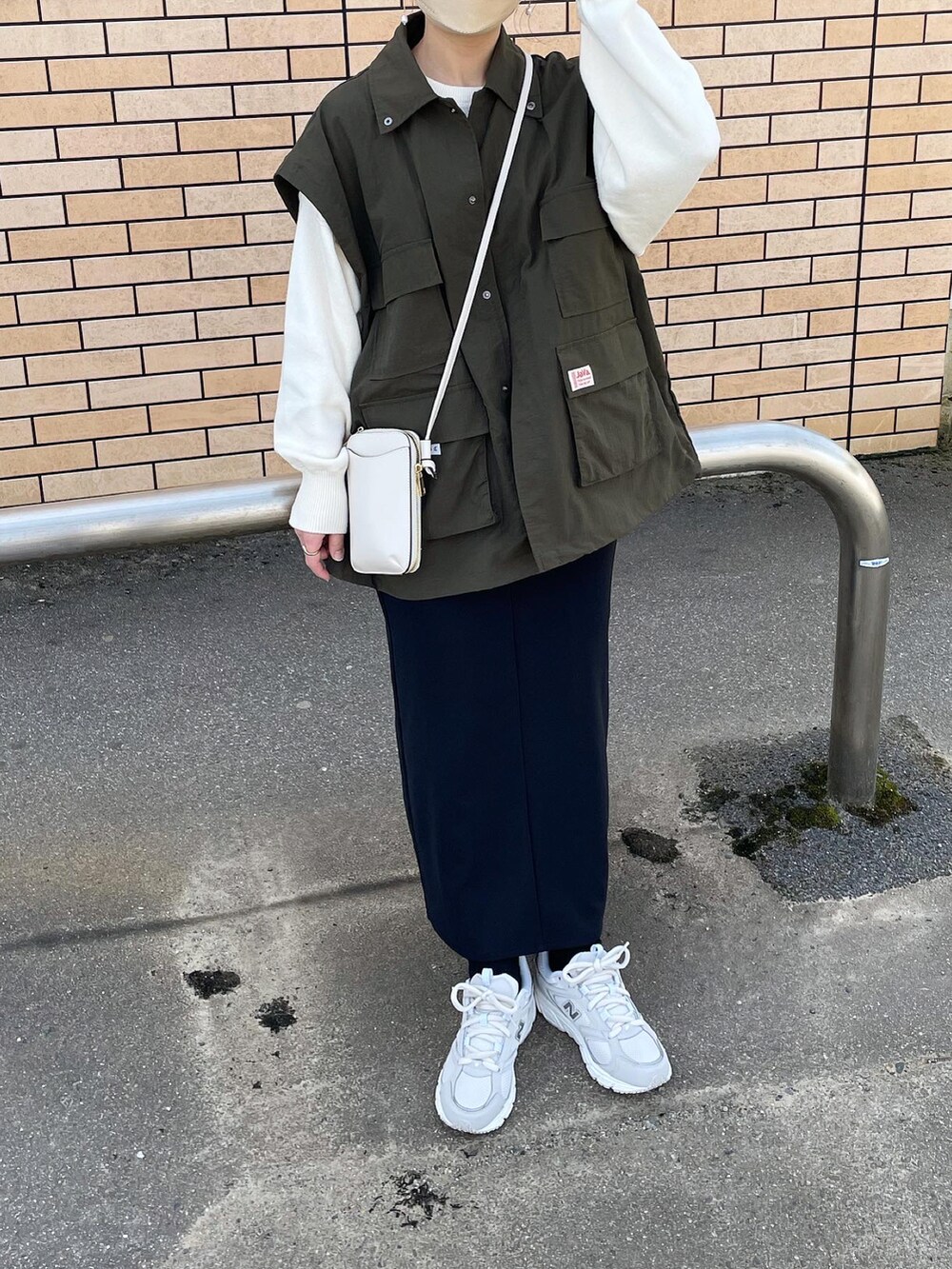 グリーン系のマウンテンパーカー、ホワイト系のニット/セーター、ブラック系のスカートを着用したレディースの春コーディネートの3枚目の写真