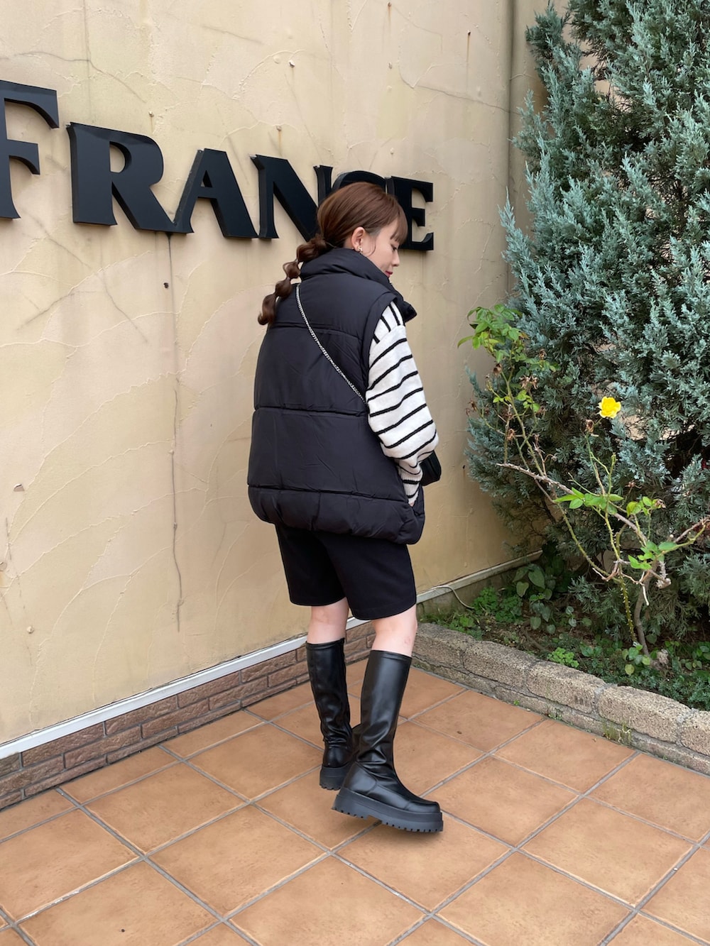 ブラック系のベスト、ブラック系のショルダーバッグ、ホワイト系のニット/セーターを着用したレディースの秋コーディネートの5枚目の写真