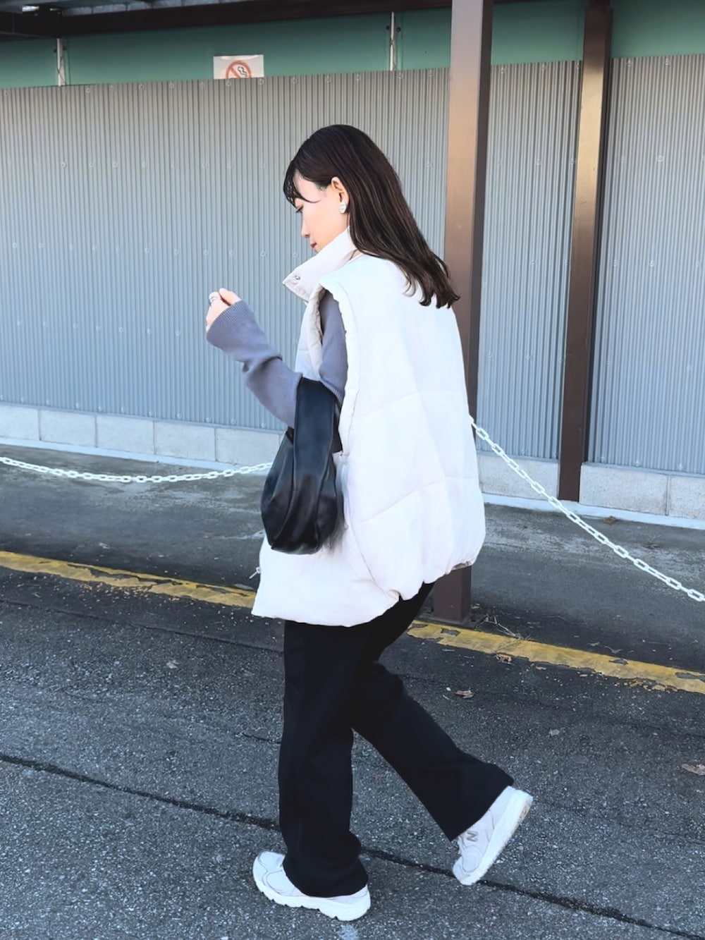 グレー系のニット/セーター、ホワイト系のダウンベスト、ブラック系のスラックスを着用したレディースの冬コーディネートの2枚目の写真