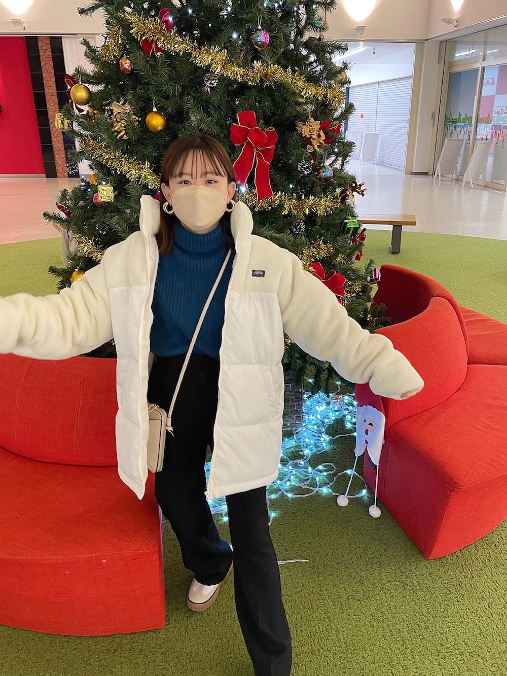 ホワイト系のダウンジャケット/コート、ブルー系のニット/セーター、ブラック系のスラックスを着用したレディースの冬コーディネートの5枚目の写真