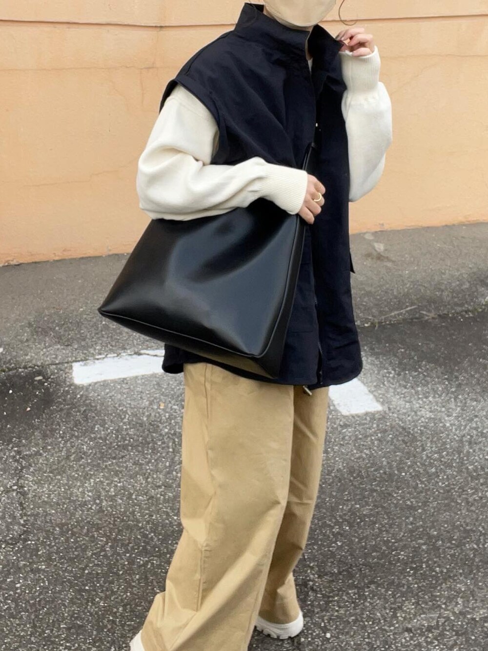 ベージュ系のその他パンツ、ホワイト系のニット/セーター、ブラック系のマウンテンパーカーを着用したレディースの春コーディネートの5枚目の写真