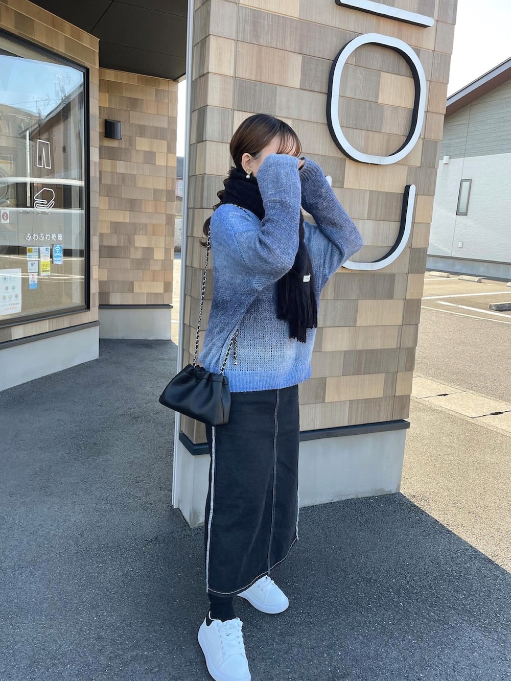 ブルー系のニット/セーター、ブラック系のショルダーバッグ、ホワイト系のスニーカーを着用したレディースの冬コーディネートの4枚目の写真