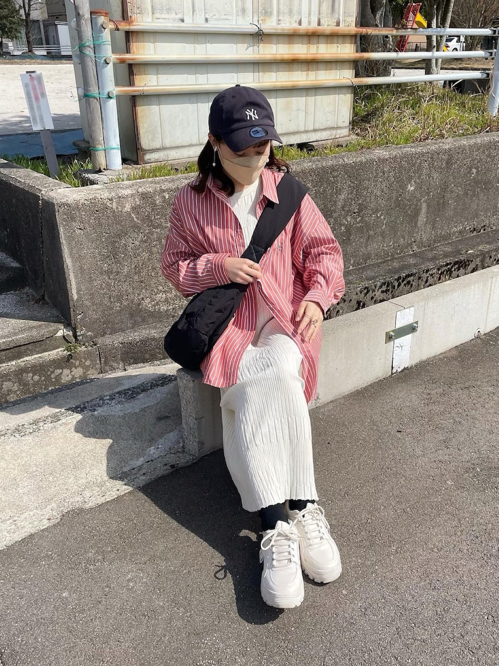 オレンジ系のシャツ/ブラウス、ホワイト系のワンピース、ブラック系のショルダーバッグを着用したレディースの春コーディネートの2枚目の写真