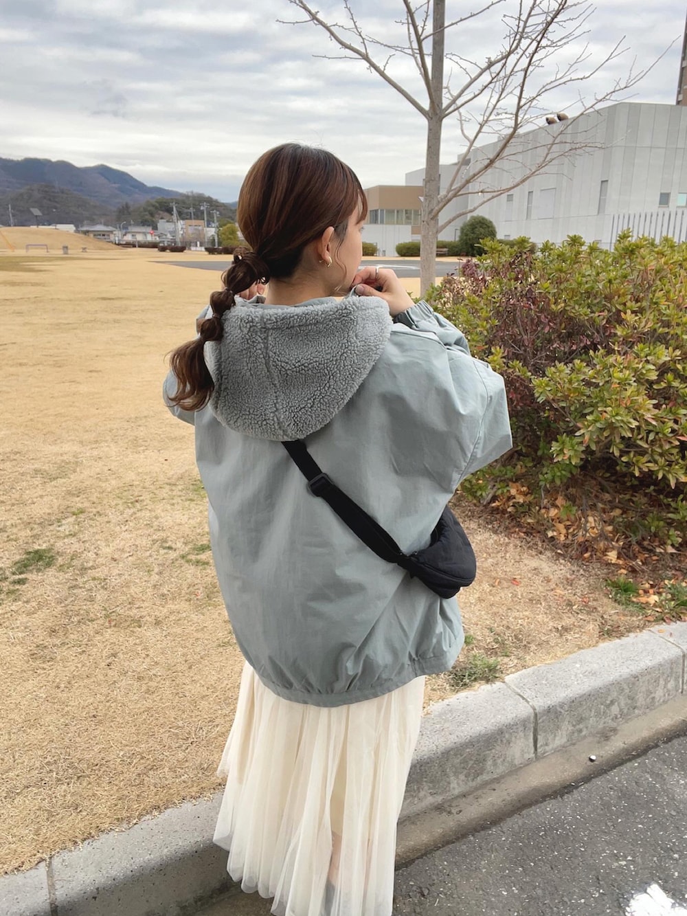 ブルー系のブルゾン、ホワイト系のスカート、ブラック系のショルダーバッグを着用したレディースの冬コーディネートの3枚目の写真