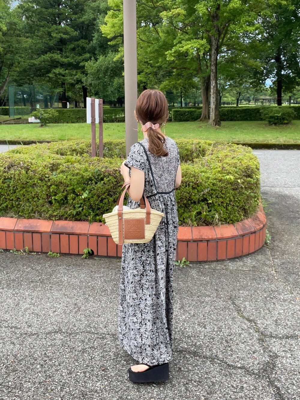 ブラック系のワンピース、ベージュ系のかごバッグ、ブラック系のサンダルを着用したレディースの夏コーディネートの2枚目の写真