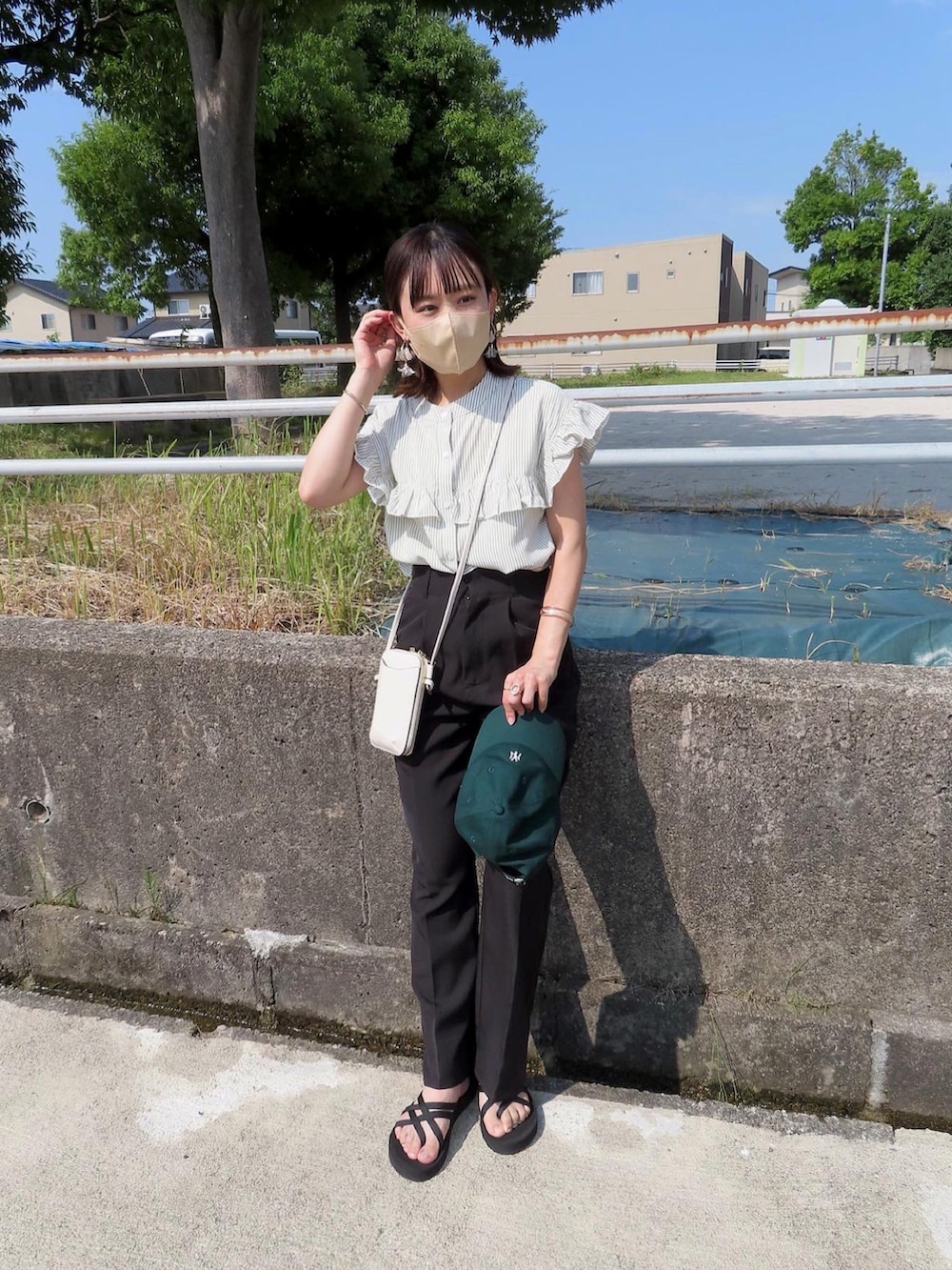 グリーン系のシャツ/ブラウス、ブラック系のスラックス、ブラック系のサンダルを着用したレディースの夏コーディネートの2枚目の写真