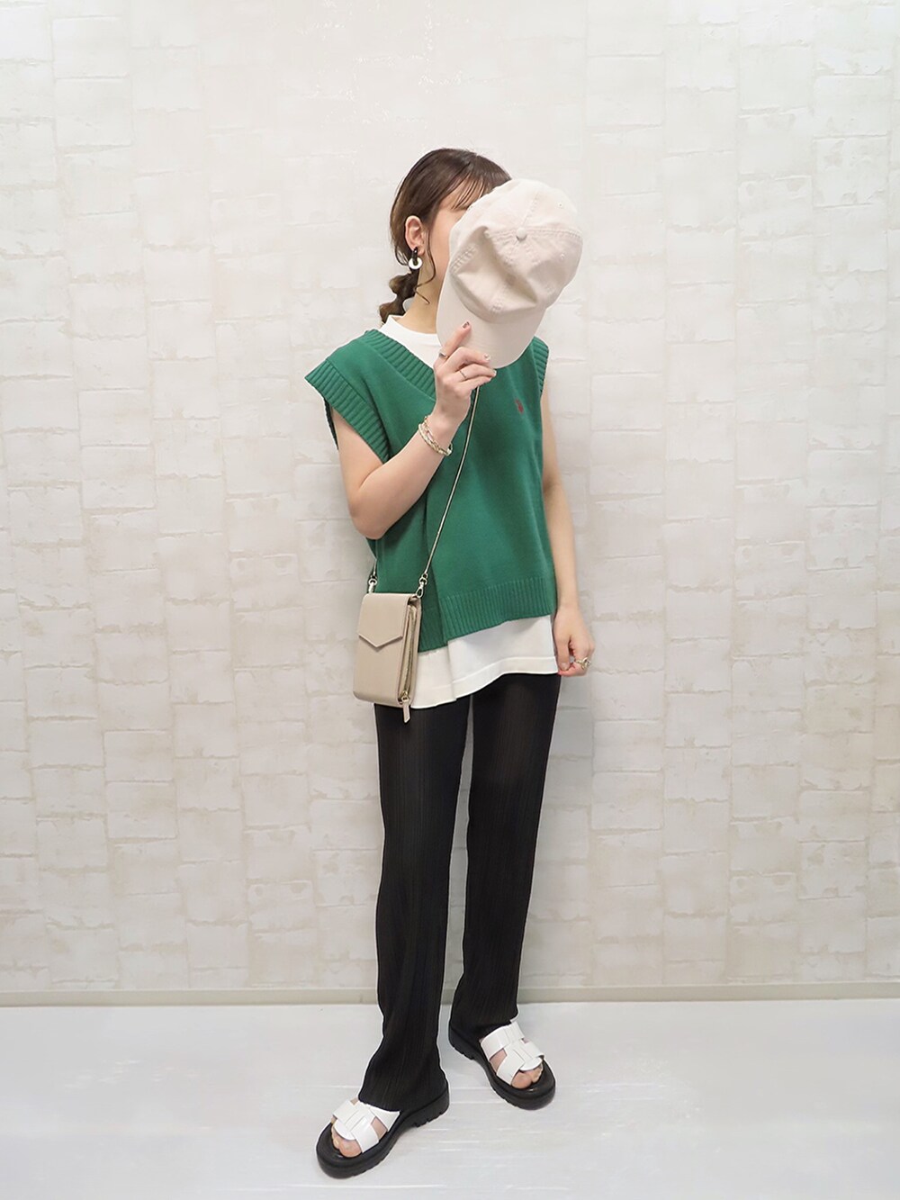 グリーン系のベスト、ホワイト系のニット/セーター、ブラック系のレギンス/スパッツを着用したレディースの春コーディネートの2枚目の写真