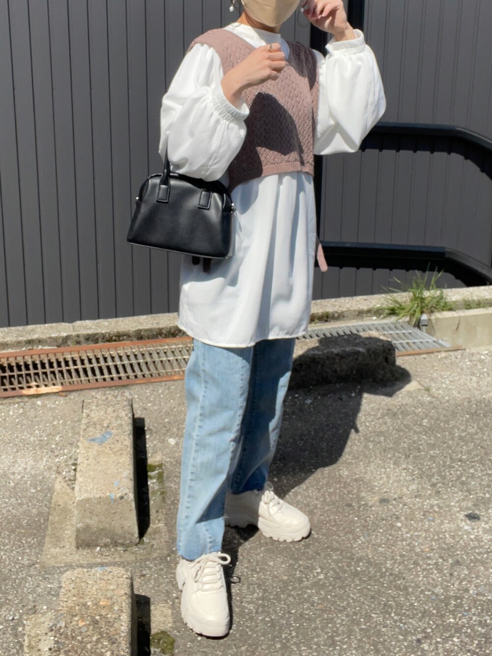 ブラウン系のベスト、ホワイト系のシャツ/ブラウス、ブルー系のデニムパンツを着用したレディースの春コーディネートの2枚目の写真