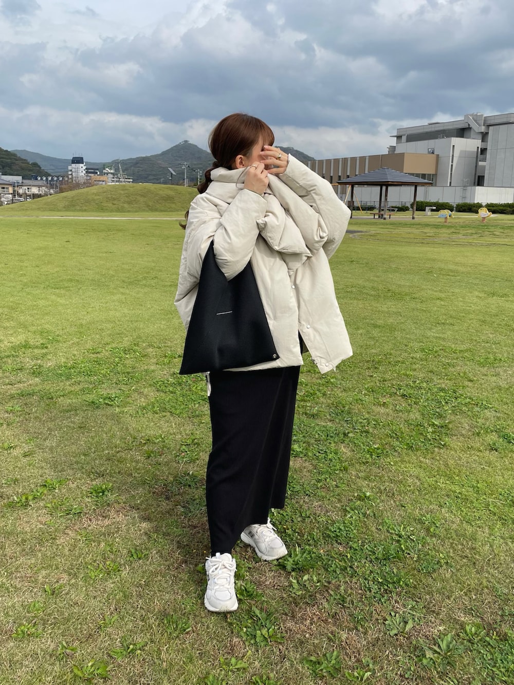 ブラック系のトートバッグ、ホワイト系のスニーカー、グリーン系のニット/セーターを着用したレディースの秋コーディネートの3枚目の写真