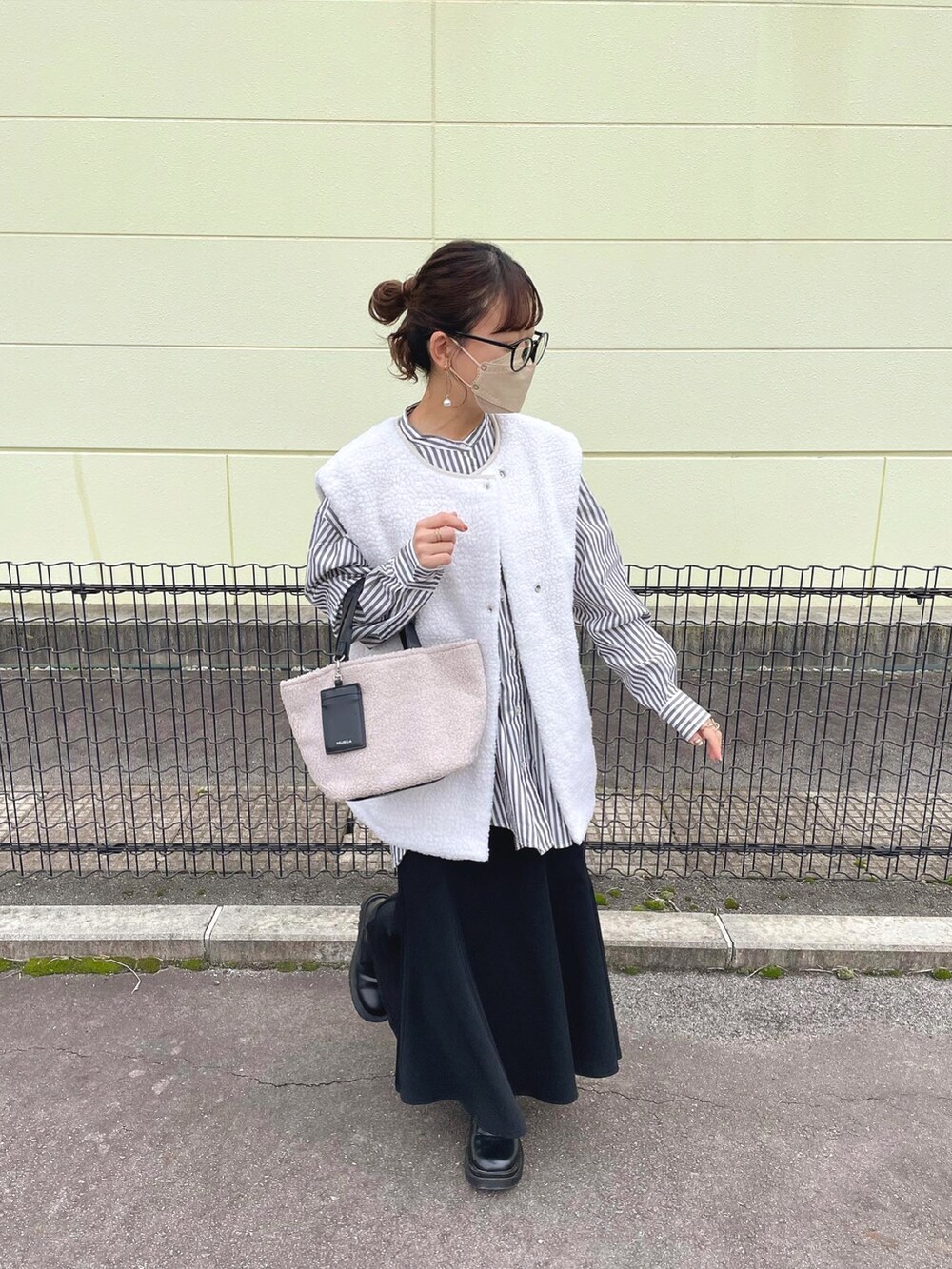 グレー系のトートバッグ、グレー系のシャツ/ブラウス、ホワイト系のベストを着用したレディースの秋コーディネートの5枚目の写真