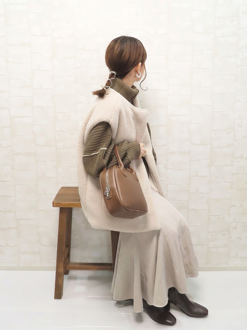 ブラウン系のニット/セーター、ベージュ系のスカート、ホワイト系のその他アウターを着用したレディースの冬コーディネートの2枚目の写真