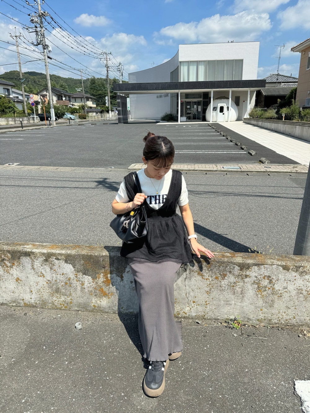 グレー系のスカート、ホワイト系のニット/セーター、ブラック系のベストを着用したレディースの秋コーディネートの4枚目の写真