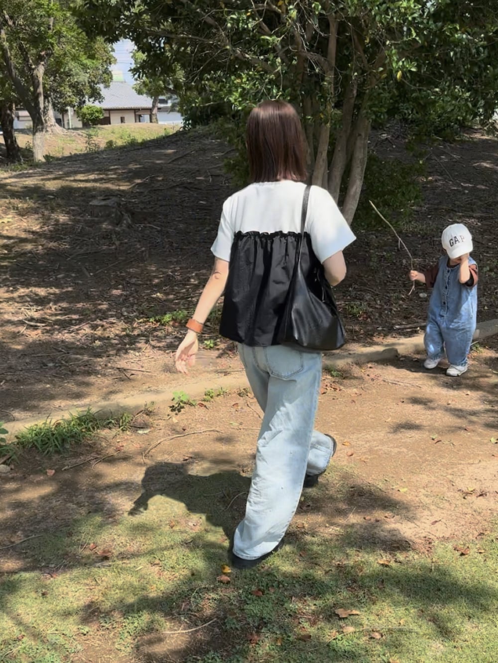ホワイト系のTシャツ/カットソー、ブルー系のデニムパンツ、ブラック系のバッグを着用したレディースの夏コーディネートの4枚目の写真