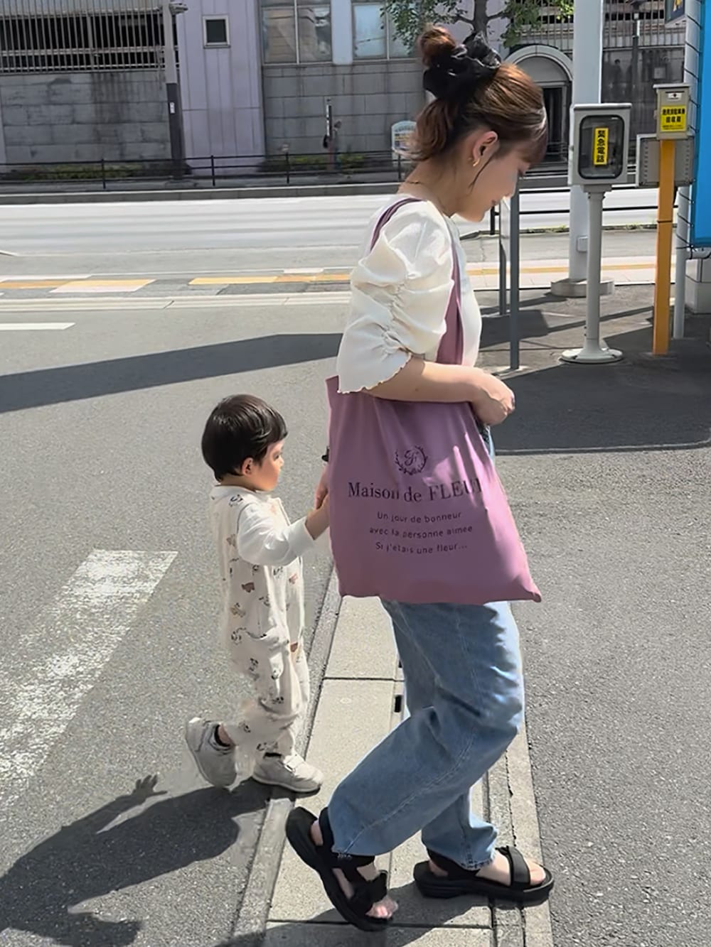 ブラック系のサンダル、ホワイト系のトップス、ブルー系のデニムパンツを着用したレディースの夏コーディネートの2枚目の写真