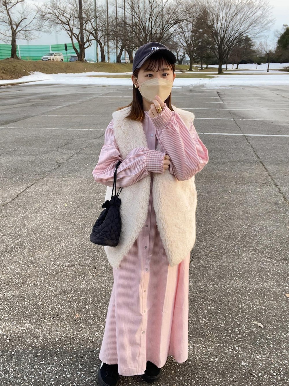 レッド系のワンピース、グレー系のベスト、ブラック系のショルダーバッグを着用したレディースの冬コーディネートの3枚目の写真