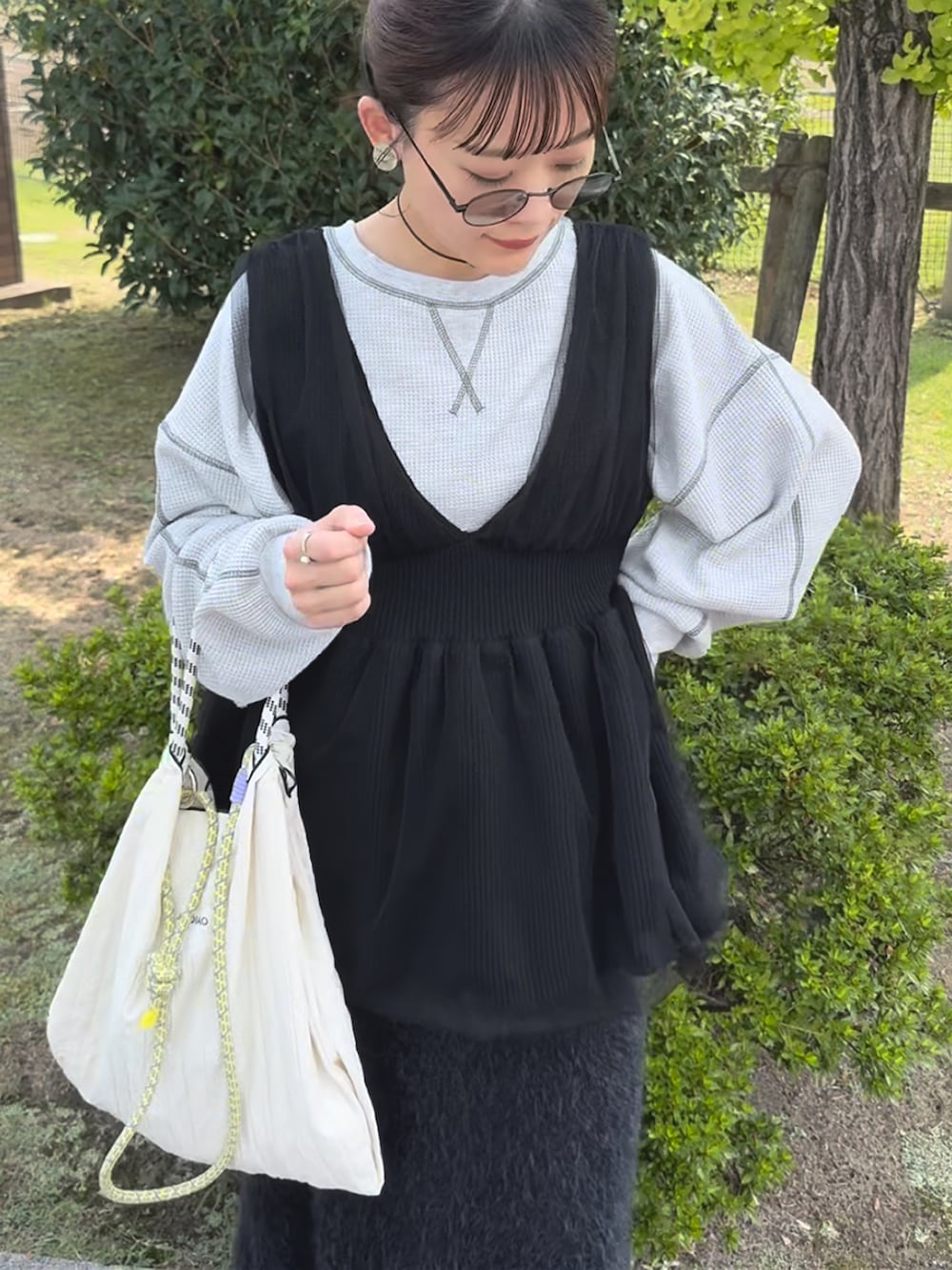 ホワイト系のショルダーバッグ、グレー系のTシャツ/カットソー、ブラック系のベストを着用したレディースの秋コーディネートの2枚目の写真