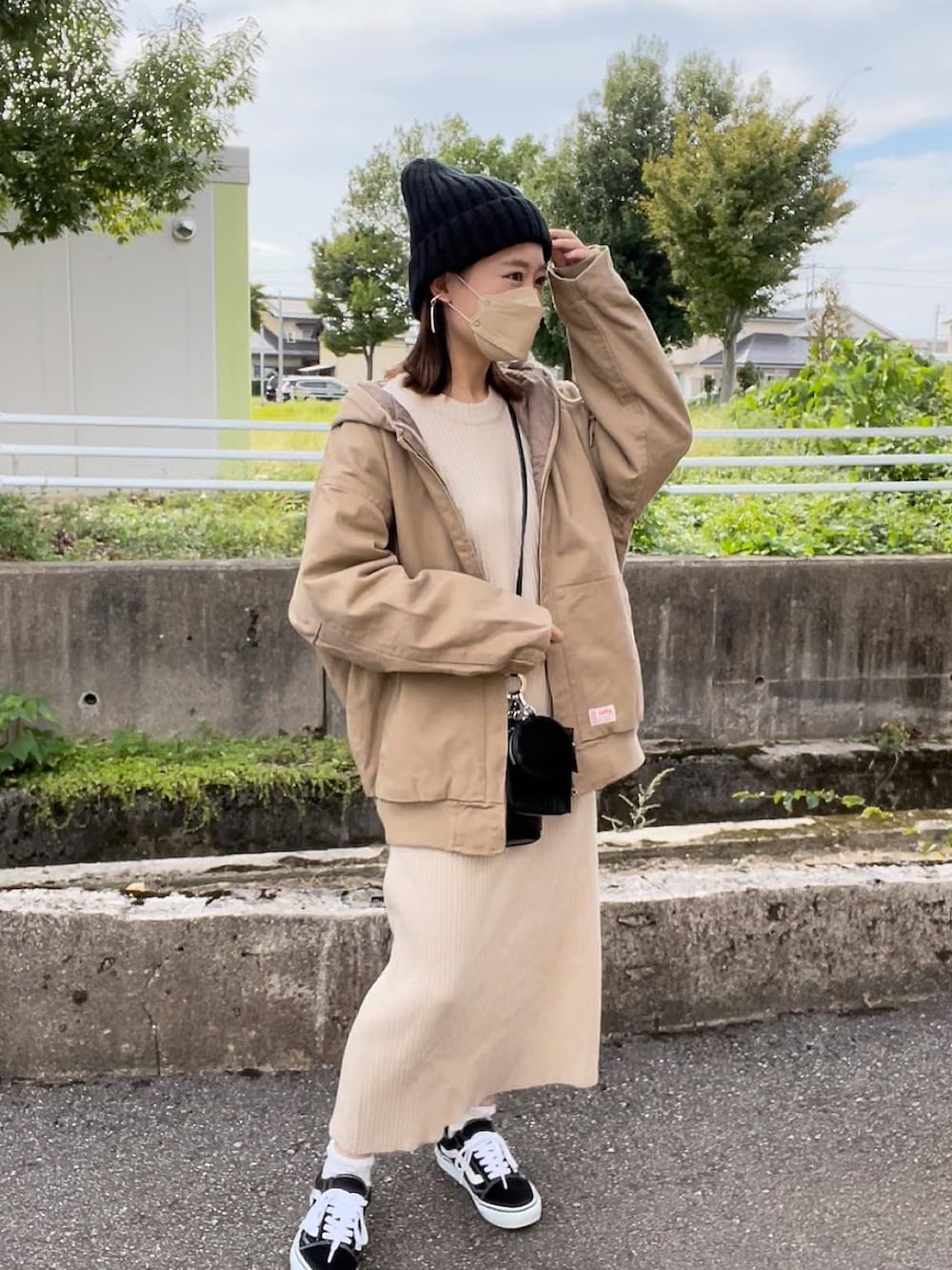 ベージュ系のブルゾン、ホワイト系のワンピース、ブラック系のショルダーバッグを着用したレディースの秋コーディネートの4枚目の写真