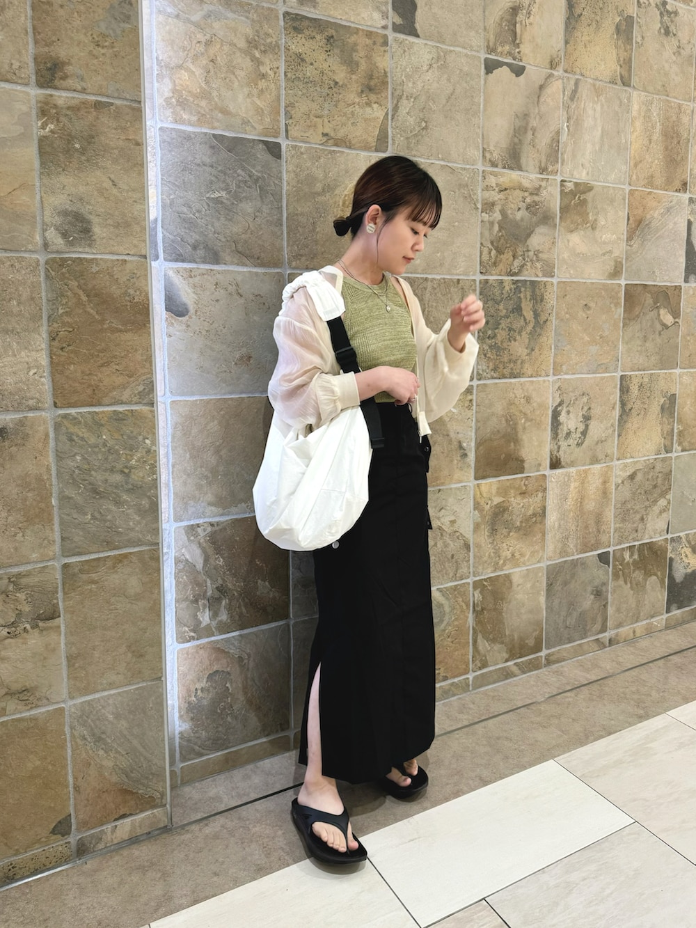 グリーン系のタンクトップ、ブラック系のスカート、ホワイト系のショルダーバッグを着用したレディースの夏コーディネートの2枚目の写真