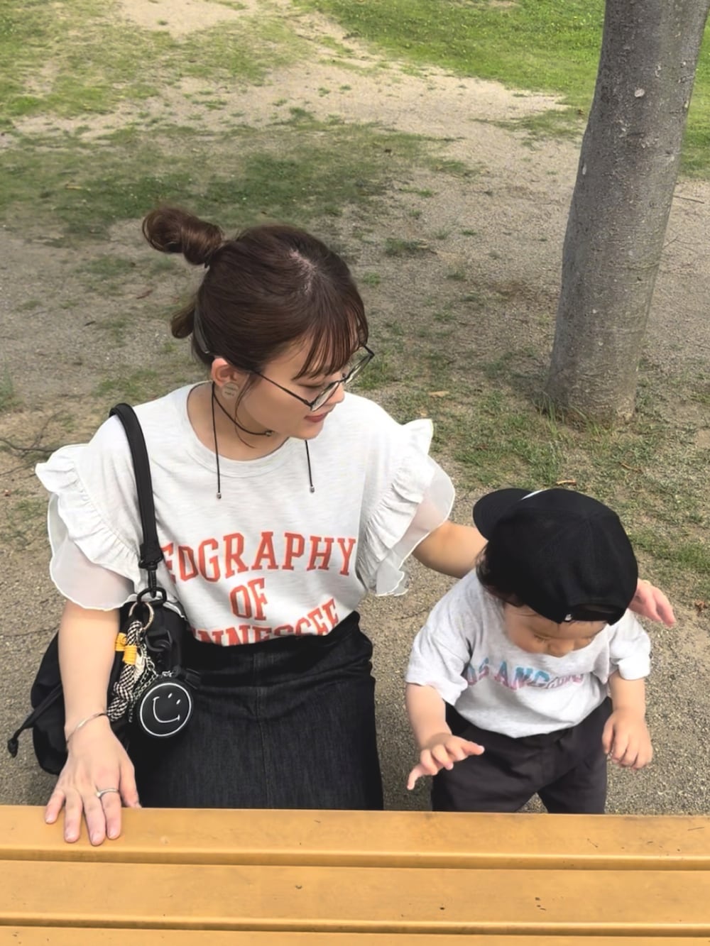 ベージュ系のTシャツ/カットソー、ブラック系のデニムスカート、ブラック系のバッグを着用したレディースの夏コーディネートの4枚目の写真