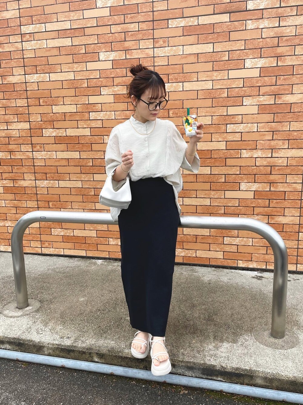 グレー系のシャツ/ブラウス、ブラック系のスカート、ホワイト系のハンドバッグを着用したレディースの春コーディネートの4枚目の写真