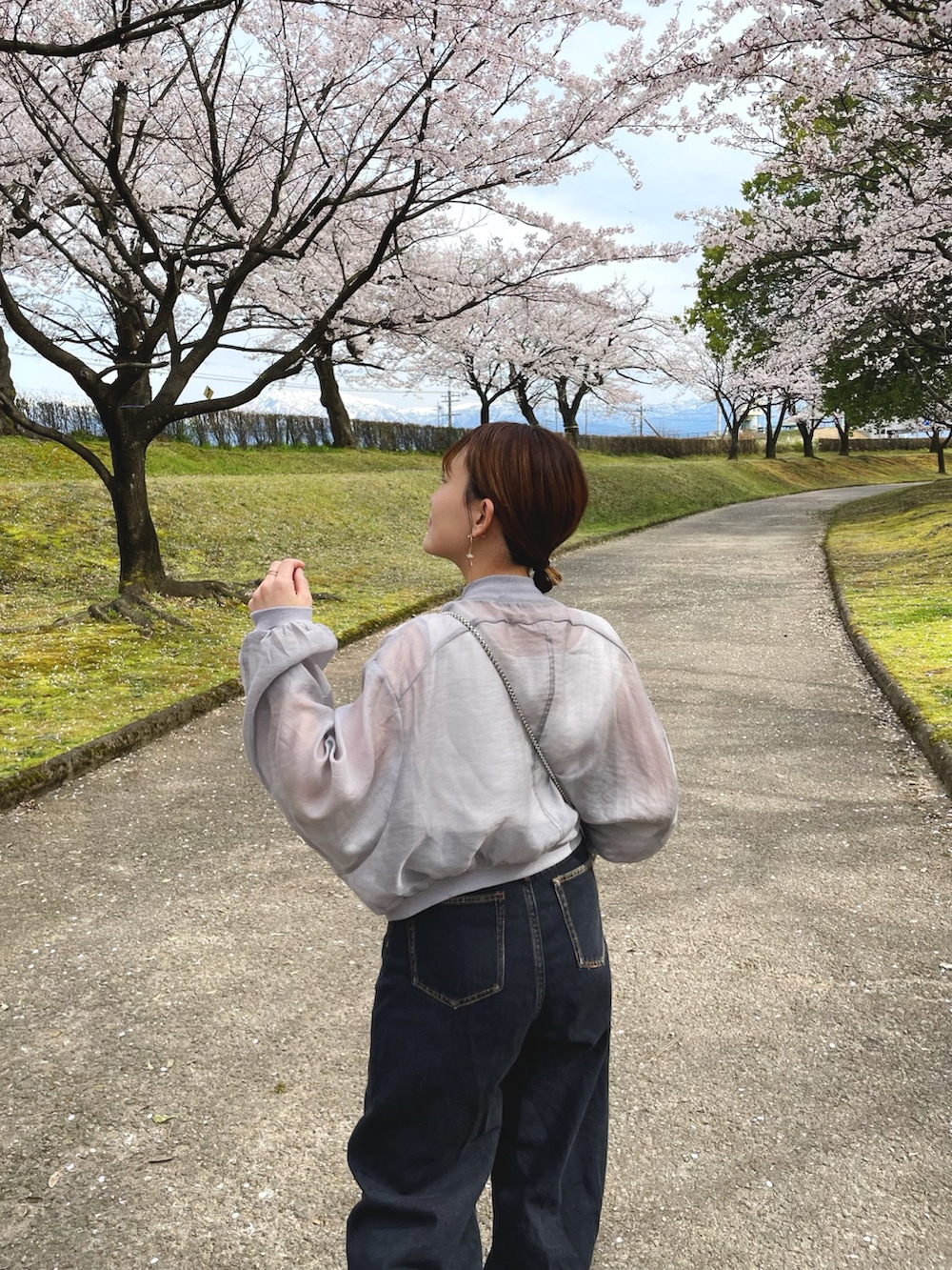 グレー系のブルゾン、ブラック系のデニムパンツ、ホワイト系のシューズを着用したレディースの春コーディネートの2枚目の写真