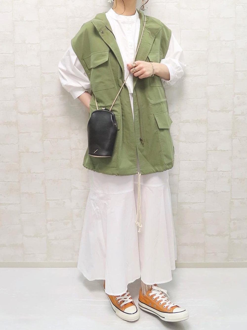 ホワイト系のワンピース、グリーン系のベスト、ブラック系のショルダーバッグを着用したレディースの春コーディネートの3枚目の写真