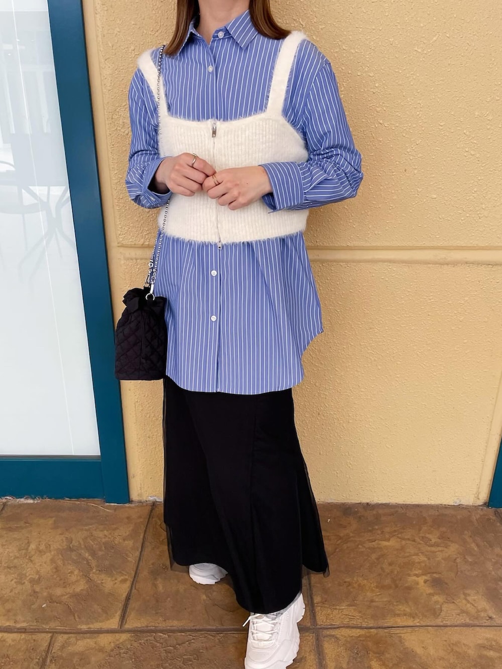 ブルー系のシャツ/ブラウス、ホワイト系のベスト、ブラック系のスカートを着用したレディースの春コーディネートの4枚目の写真