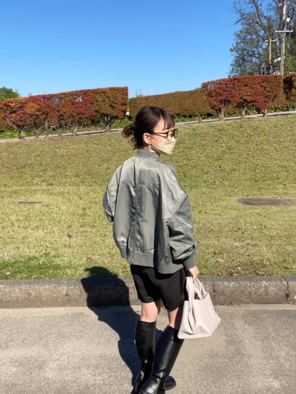 グリーン系のブルゾン、ホワイト系のニット/セーター、ブラック系のスラックスを着用したレディースの秋コーディネートの5枚目の写真