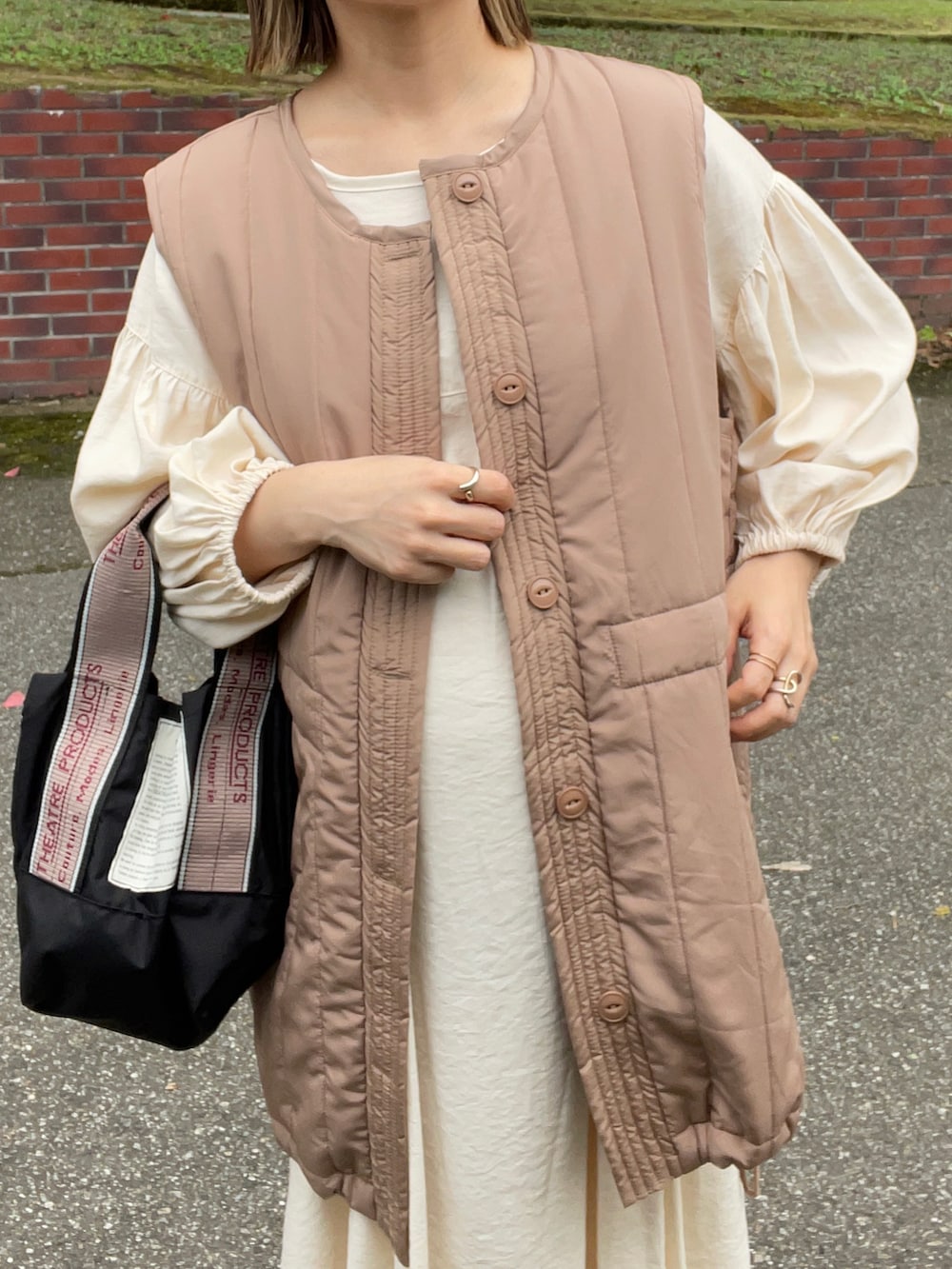 ベージュ系のベスト、ホワイト系のワンピース、ブラック系のショルダーバッグを着用したレディースの秋コーディネートの4枚目の写真