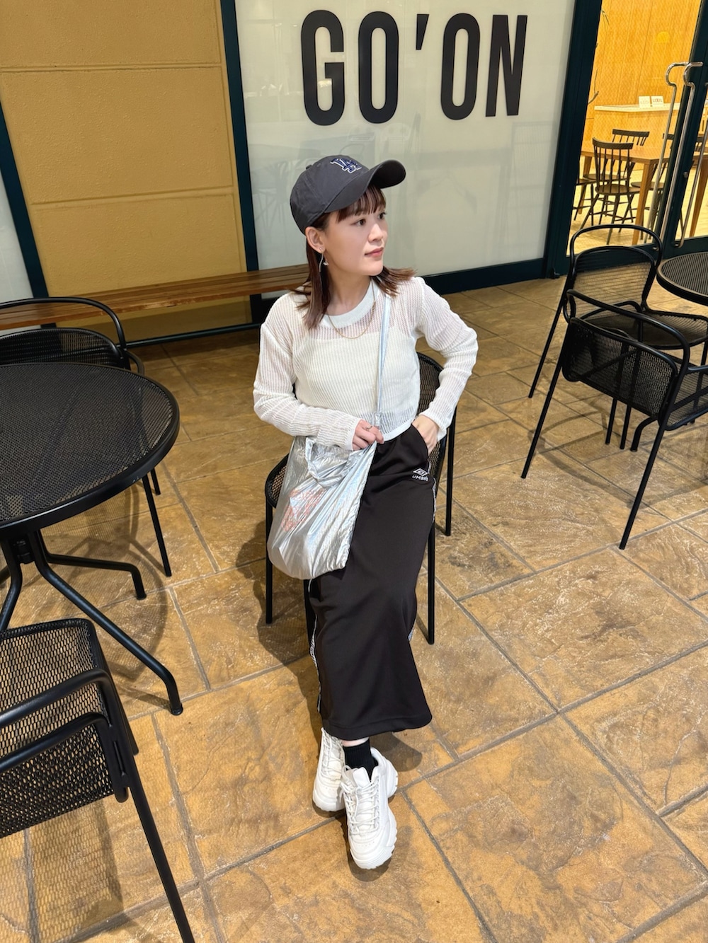 ホワイト系のトップス、ブラック系のスカート、シルバー系のトートバッグを着用したレディースの春コーディネートの5枚目の写真