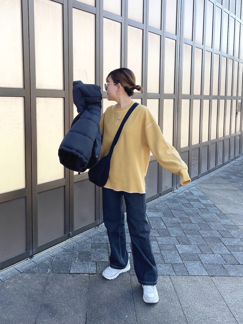 ブラック系のダウンベスト、イエロー系のTシャツ/カットソー、ブラック系のデニムパンツを着用したレディースの冬コーディネートの5枚目の写真