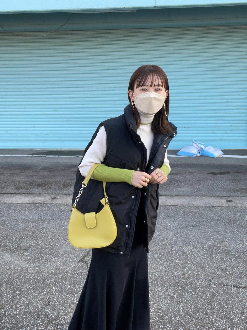 ホワイト系のニット/セーター、ブラック系のダウンベスト、ブラック系のスカートを着用したレディースの秋コーディネートの4枚目の写真