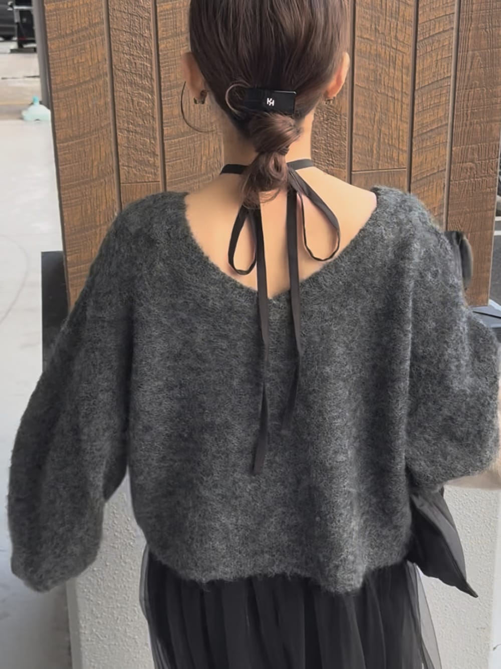 グレー系のワンピース、ブラック系のダウンベスト、ホワイト系のバッグを着用したレディースの冬コーディネートの4枚目の写真