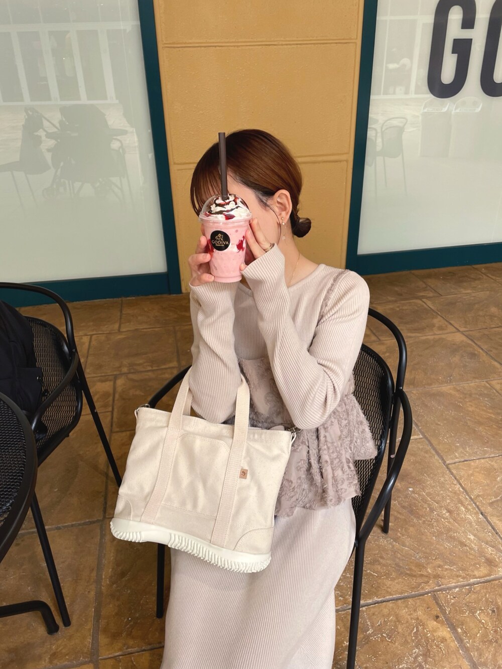ホワイト系のトートバッグ、ベージュ系のワンピース、ホワイト系のシューズを着用したレディースの春コーディネートの3枚目の写真